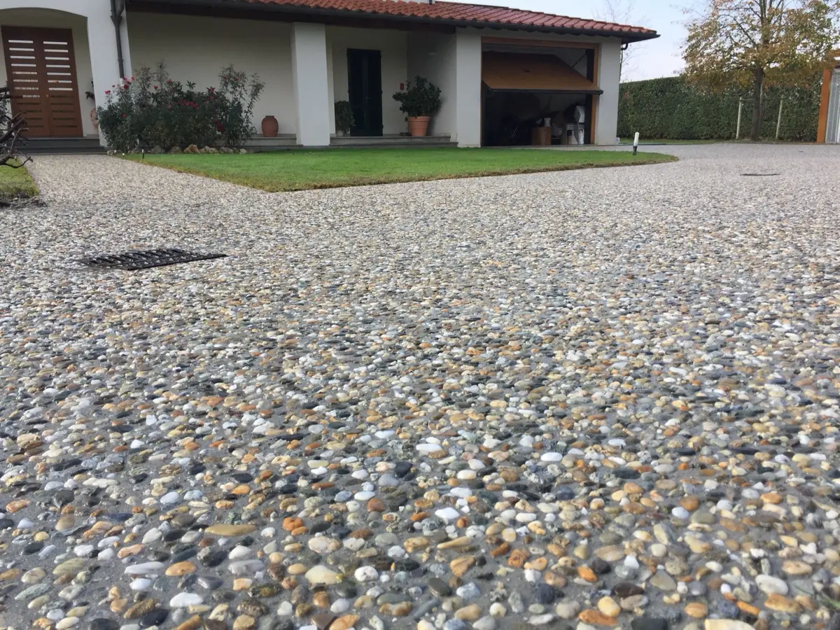 Corte in sasso lavato davanti a una villa con il prato