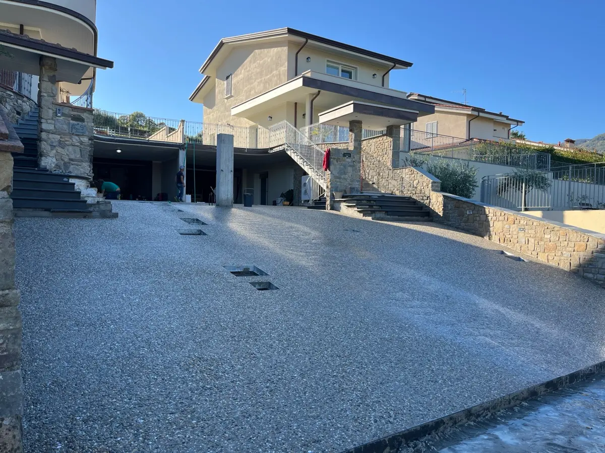Ampio cortile residenziale in sasso lavato davanti a una casa