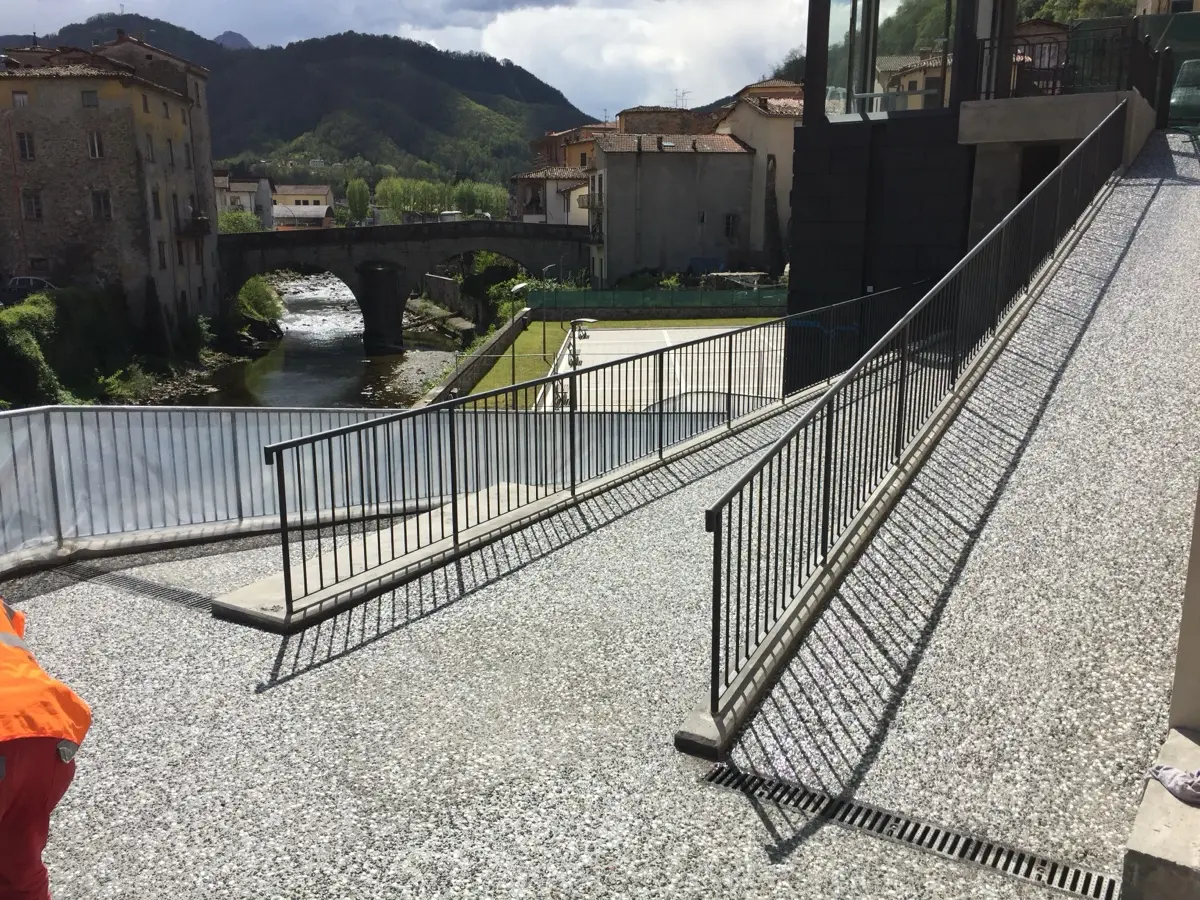 Rampa in sasso lavato con ringhiera, affacciata sul fiume