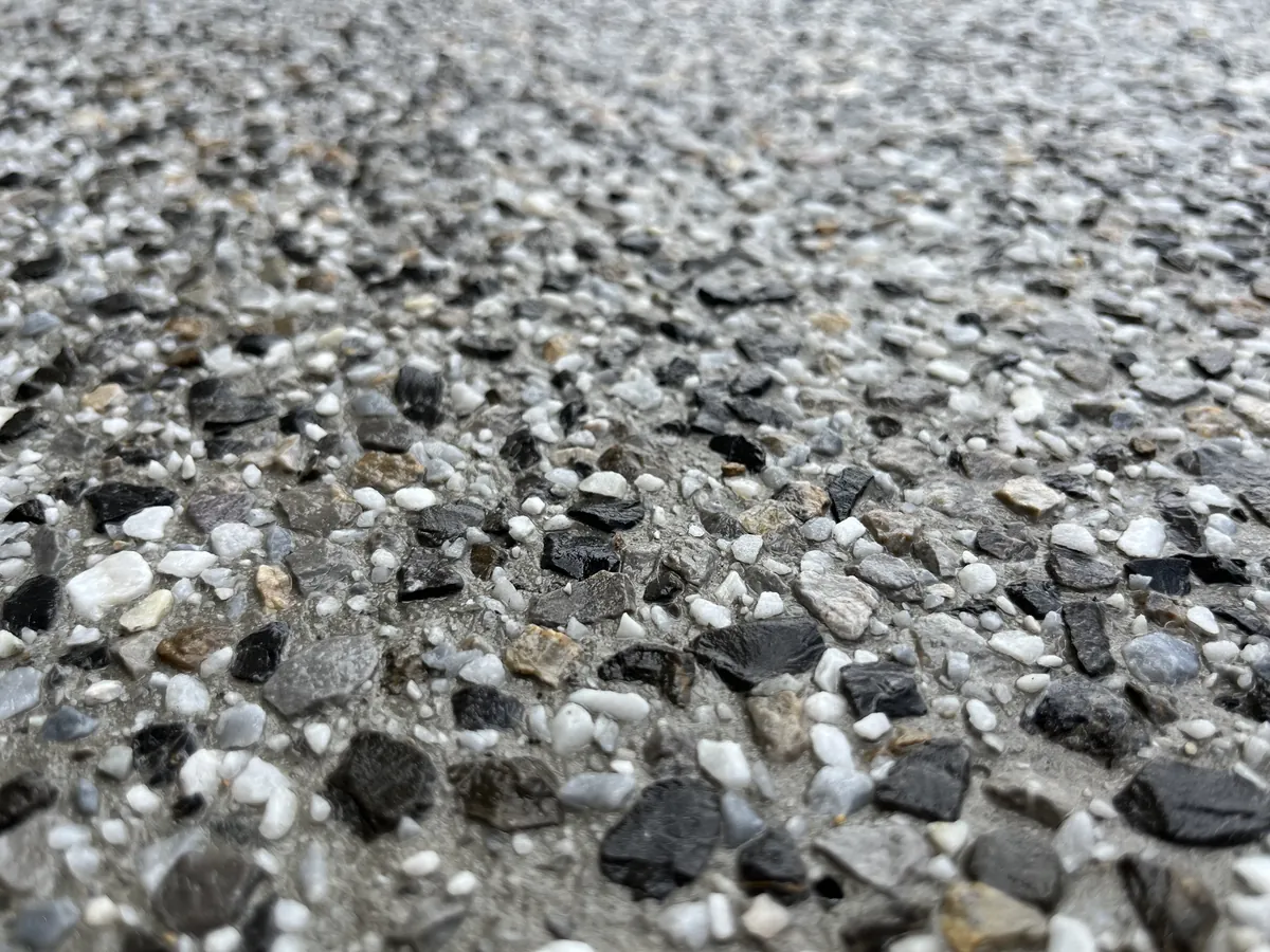 Dettaglio ravvicinato di un pavimento in sasso lavato con aggregati chiari e scuri