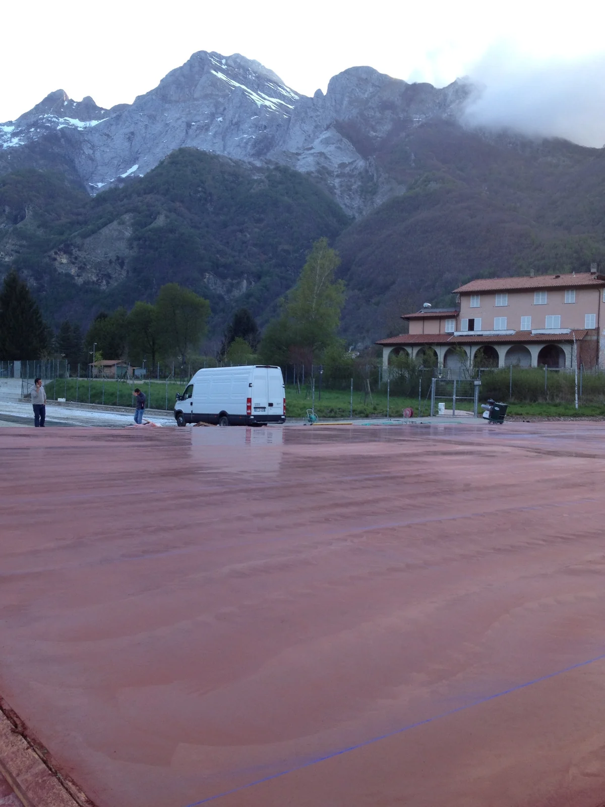 Piazzale in calcestruzzo colorato rosso appena lisciato, con le montagne sullo sfondo