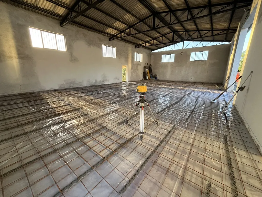 Livello laser su treppiede sull'armatura di un capannone, per fissare le quote del pavimento